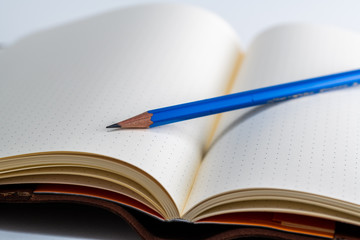 An open blank paper notebook with a pencil 
