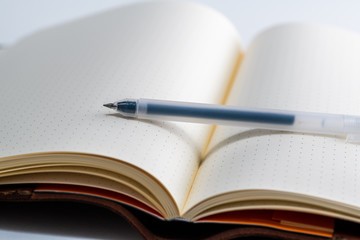 An open blank paper notebook with an uncapped ink pen 