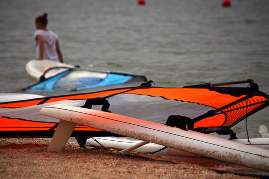 One windsurfer, a woman, is preparing to go to sea on a cloudy day. Selective focus, copy space.