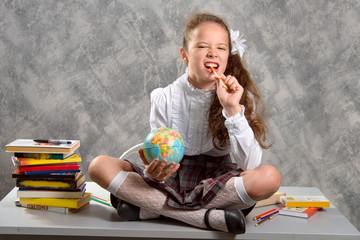 The fidget schoolgirl in school uniform sits on table and smiles happily. The new school year....