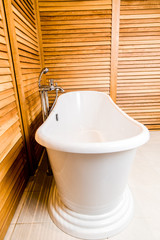 Wooden bathroom interior with white tub
