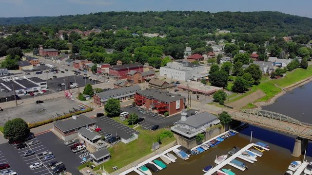 A slow forward aerial establishing shot of a small town in Pennsylvania on a summer day. Marina in the foreground. Pittsburgh suburbs.  	