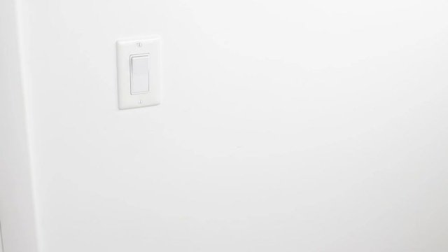 Male Hand Turning On and Off a Flat White Light Switch on a Wall