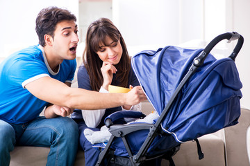 Young parents with their newborn baby in baby pram sitting on th