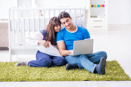 Young parents with their newborn baby sitting on the carpet 