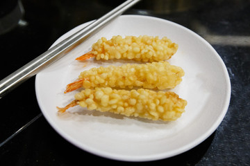 shrimp in tempura on the white plate and metal chopsticks