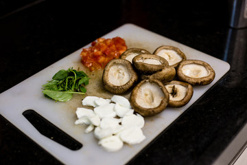 chopping board with mushrooms, basil, tomatoes and other vegetables as ingredients