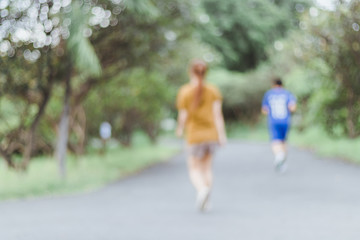 Defocused, blurred motion background of summer activities with energetic people jogging, walking, running at green city park. Healthy lifestyle concept.