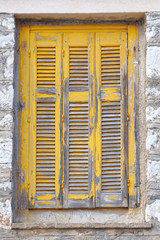 old wooden window yellow shutters on stone wall
