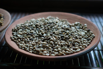 Closeup of raw beans of luwak coffee in the big clay dish. One of the steps of preparing of the most expensive coffee in the world