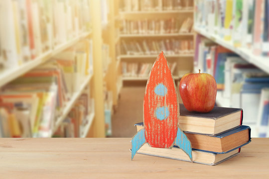 Back to school concept. rocket and books in front of blurry Library background.