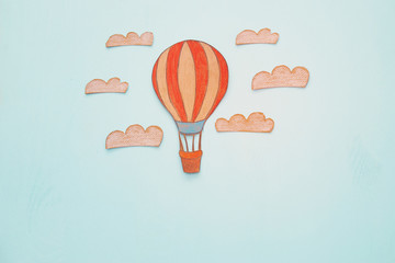 Hot air balloon, space elements shapes cut from paper and painted over wooden blue background.