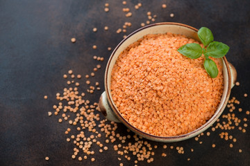Bowl with raw dried red lentil on a brown metal background, elevated view with copyspace, horizontal shot
