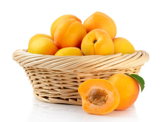Fresh apricots in the basket are isolated on a white background.