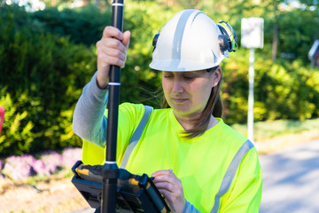 Close up of woman in reflective clothing using GPS land surveying tool with screen