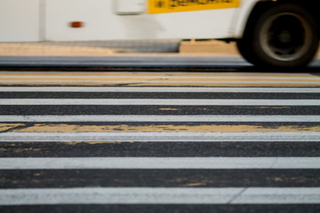 a lower part of a car moving through a zebra crossing