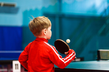 a child plays table tennis in the gym - obrazy, fototapety, plakaty