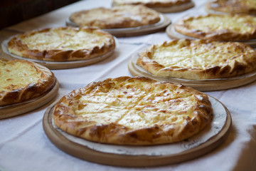 hot appetizing delicious pies topped with cheese and laying on a long table covered with white tablecloth