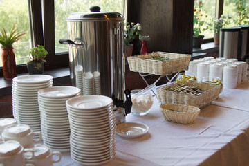 white dishes with bakery on the table with flowers on a window sill on the background