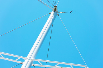 Fototapeta premium The upper part of the white masts of yachts without sails against the blue cloudless sky