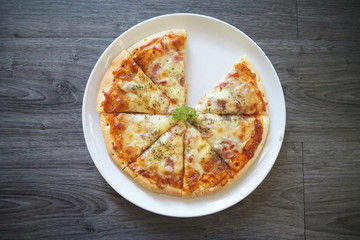 Bake Pizza ham and grilled mozzarella cheeses decorate on top with coriander on white dish with gray wooden ready to serve