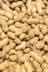 Peanuts in shell texture background. Raw peanuts on display at a farmer's market. unpeeled peanut background. Vertical photo