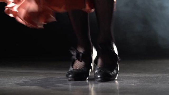 Legs of the girl are tap dancing. Light from behind. Smoke background. Close up