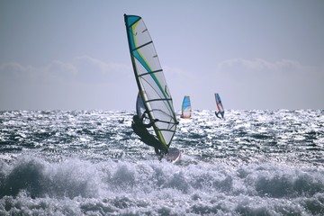 Naklejka premium Windsurfers at the Atlantic ocean glistening in the sun with shorebreak in front
