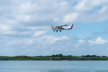 Fototapeta na wymiar A small plane flying above the lake