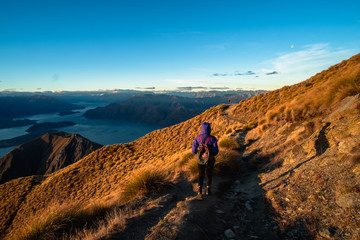 A hiker hiking on the beautiful track with a landscape of the mountains and Lake Wanaka. Roys Peak...