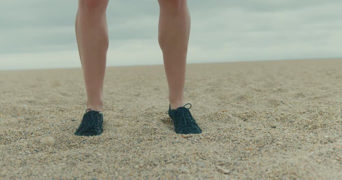 Legs of a young fitness woman jumping on the beach