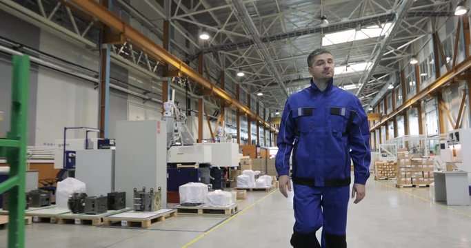 Engineer in in blue uniform is Walking Through Factory. front View