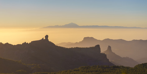 Silhouettes of Roque Nublo and Bentayga against sunset light. Pico de Teide on background. Gran...