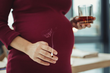 Harmful habit. Young pregnant irresponsible woman having bad habits and smoking while drinking...