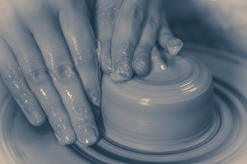 Photo in old vintage style. Creating ceramic products of white clay close-up. The sculptor in workshop makes clay jug closeup. Master crock. Twisted potter's wheel. Cultural tradition Master's Hands