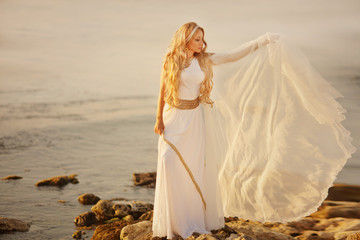 Beautiful girl in a long white wedding dress in Greek style is the old Greek goddess