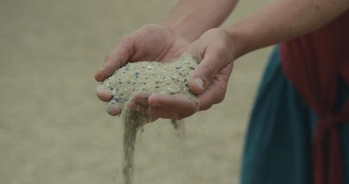 Sand falling through the fingers of a young woman