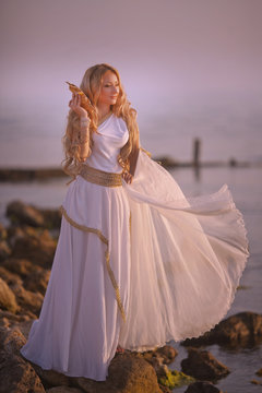 Beautiful girl in a long white wedding dress in Greek style is the old Greek goddess