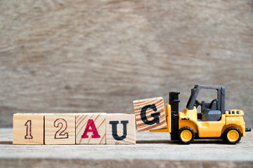 Toy forklift hold block G to complete word 12 aug on wood background (Concept for calendar date in month August)