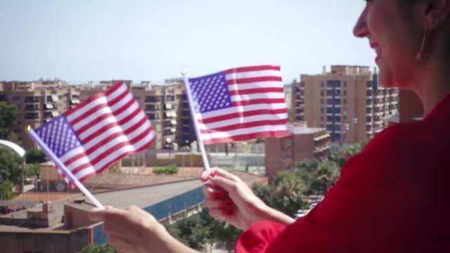 Red dressed woman waving USA national flag hand and celebrating a patriotic and american national holiday like 4ht of July, Flag day, national day or memorial day.Slow motion from 120 fps original cli