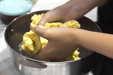 The chef's hands knead the dough in a steel bowl
