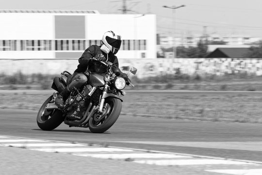 Man in a black jacket and grey pants race on a motorcycle. Motion blur. Black and white image.