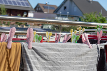 Bunte Kleidungsstücke auf dem Wäscheständer mit farbigen Wäscheklammern zum Trocknen