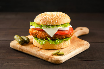Hamburger lies on a cutting board on a wooden background.