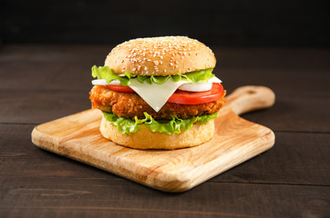 Hamburger lies on a cutting board on a wooden background.