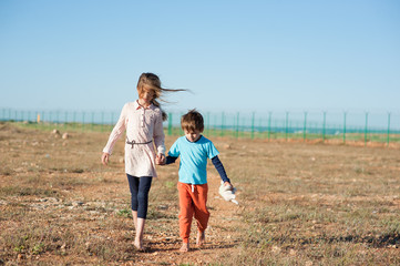 two kids migrants walking in desert shoeless with plush toy along state border