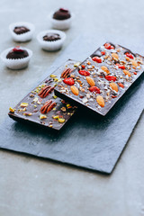 Raw homemade chocolate with nuts, cranberris on black background