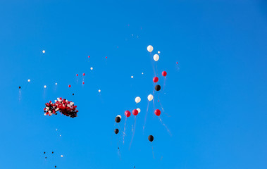 party balloons floating away into a blue sky