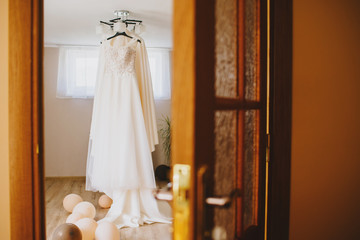 Beautiful wedding dress hanging on the chandelier in the room