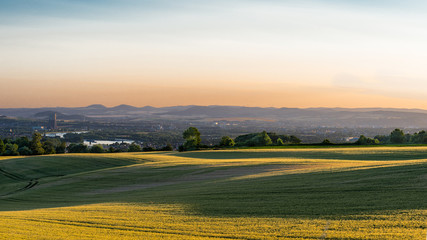 Panorama of the beautiful sunset in western Germany, a field of wheat, in the distance a flowing river, railway bridge and chimney of a nuclear power plant.